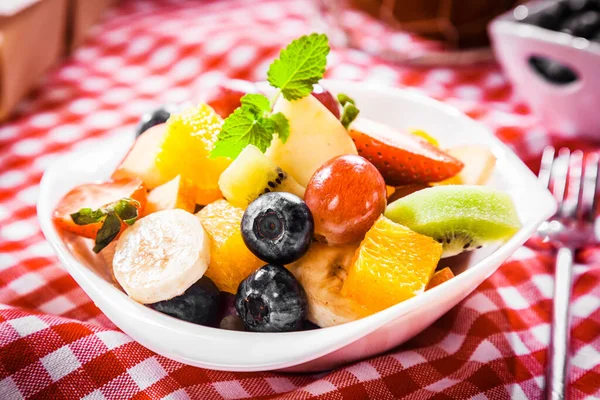 健康的な夏のピクニックのためのブルーベリー キウイフルーツ オレンジ リンゴ バナナ ブドウとオレンジとトロピカルフルーツサラダのカラフルなボウル — ストック写真