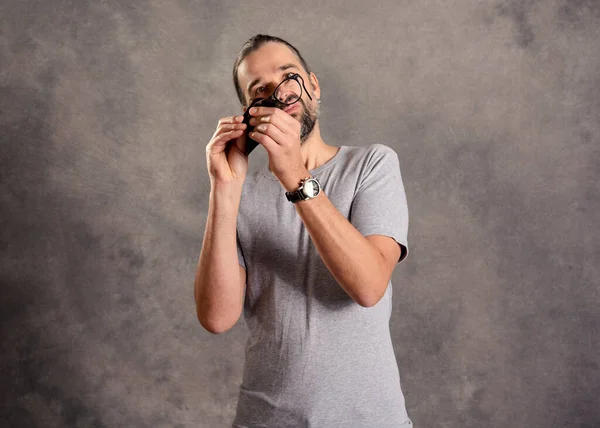 Νεαρός Γενειοφόρος Άνδρας Που Στάζει Γυαλιά Του Μπροστά Από Γκρι — Φωτογραφία Αρχείου