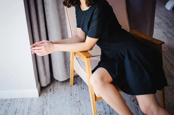 年轻迷人的女人 穿着黑色雅致的衣服 坐在房间内靠窗的椅子上 — 图库照片