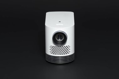 Stylish mini home cinema LED projector, lightweight tech gadget, front view. clipart