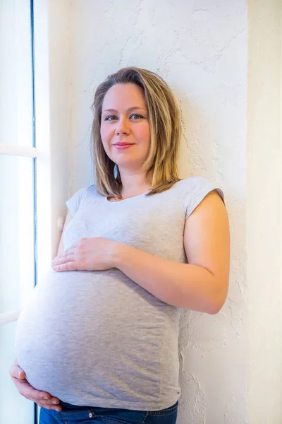 怀孕妇女站在家里靠窗的地方 — 图库照片