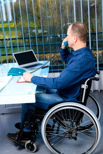 坐在轮椅上的残疾商人在办公室工作 — 图库照片