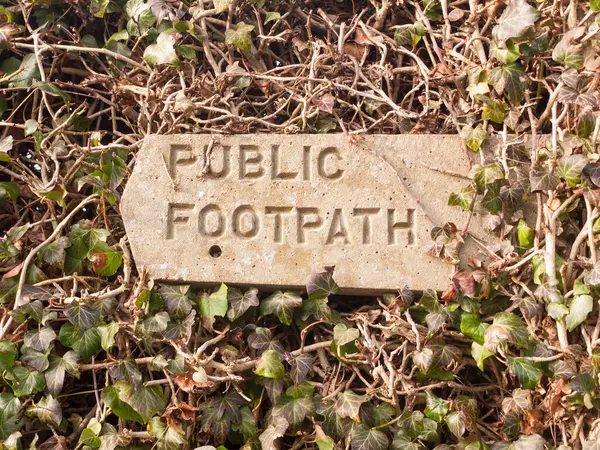 public footpath sign post stone in hedgerow direction pointer