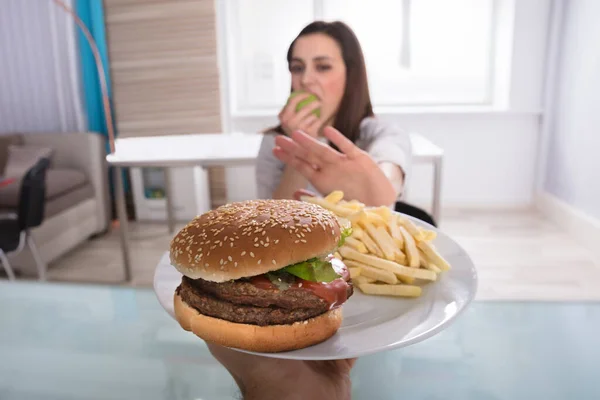 Νεαρή Γυναίκα Αρνείται Burger Και Γαλλικές Πατάτες Ενώ Τρώει Φρούτα — Φωτογραφία Αρχείου