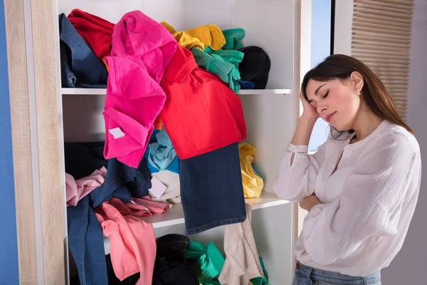 一个年轻女人睡在架子上脏兮兮的衣服旁边的侧视图 — 图库照片