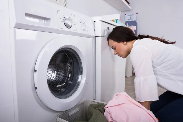 洗濯機の他に排出される若い女性と洗濯室で服でいっぱいのバスケット — ストック写真