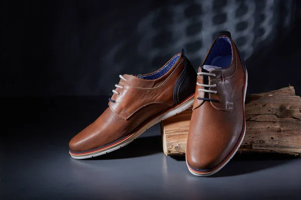 Fashion shoes, new brown polished classic shoes for men on a dark background.