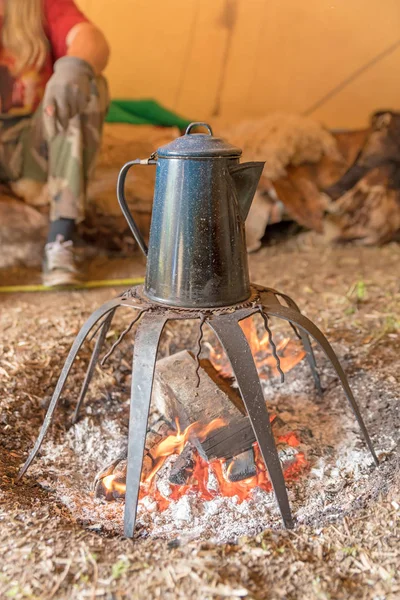 板金製の古いコーヒーポットはラックの上のキャンプファイヤーの上に立っています — ストック写真