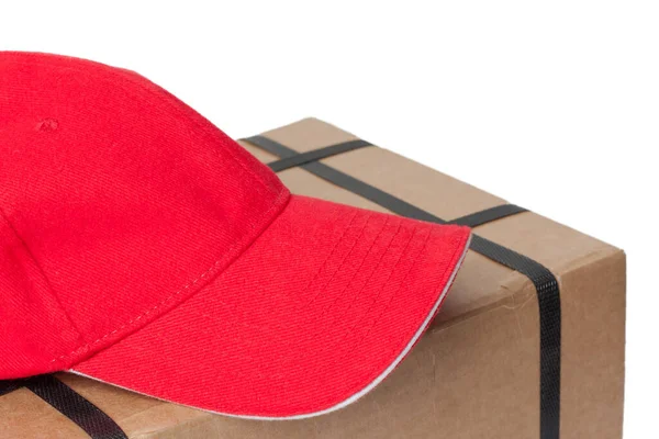 白い背景に隔離された上に横たわる郵便配達人の帽子を持つ小包 — ストック写真