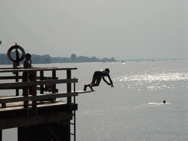 Silhouet Van Een Man Die Bij Zonsondergang Van Pier Springt — Stockfoto