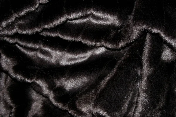 Highly detailed background texture of black fur made of synthetic animal  long hair. Stock Photo