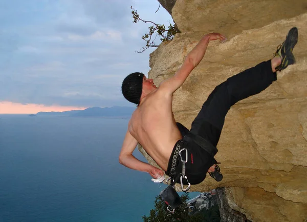 Young Man Climbing Cliff Stock Image