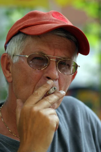グラスとキャップの煙を持つ老人 — ストック写真