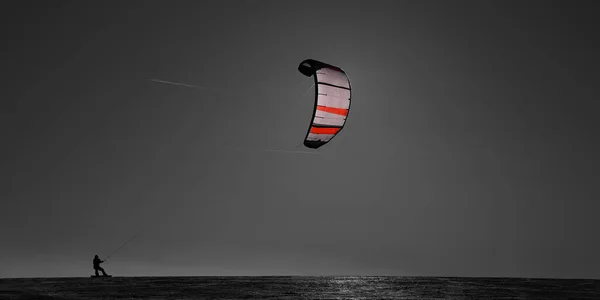 ビーチで凧に乗っている男のシルエットは — ストック写真