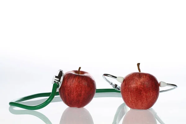 赤いリンゴと白い背景の聴診器は — ストック写真