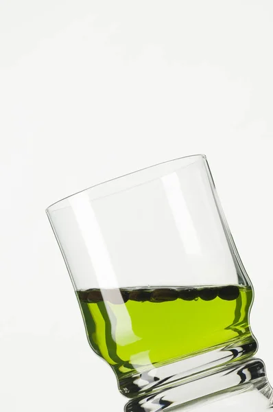 Studio Inspelning Lutande Glas Med Grön Vätska Mot Vit Bakgrund — Stockfoto