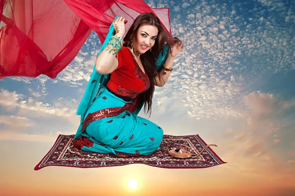 伝統的な服を着た美しい若いインド人女性が空飛ぶカーペットの上に座って — ストック写真