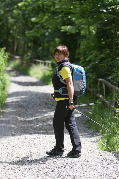 Woman with walking sticks on a forest path