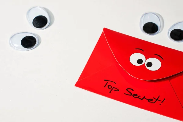 白い背景にプラスチック製の目を動かす2組のペアは トップシークレット という言葉で赤い封筒を見てください — ストック写真