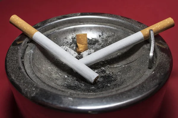 两根香烟和烟灰缸里的一角 — 图库照片