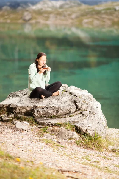 Μια Γυναίκα Κάθεται Μια Πέτρα Στην Ακτή Της Λίμνης Και — Φωτογραφία Αρχείου