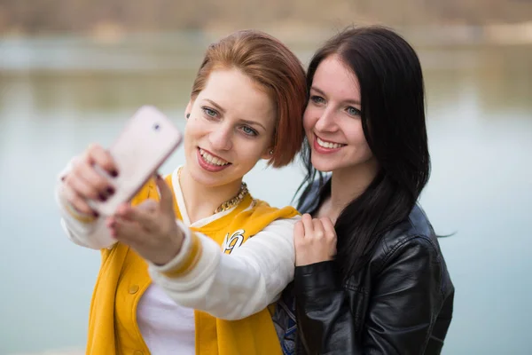 2人の若い女性がスマートフォンで写真を撮る — ストック写真