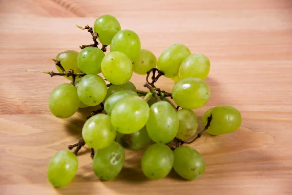木制底座上的一串新鲜绿色葡萄 — 图库照片