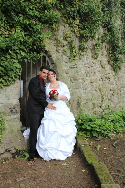 新しく結婚した夫婦は壁の前でポーズをとる — ストック写真