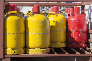 Yellow and red metal propane gas bottles standing on a pallet clipart