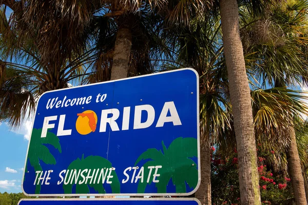 Florida, USA: Welcome to Florida sign next to highway with palm trees around