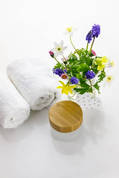 在白色背景前的奶瓶旁边的毛巾和花瓶里的花 — 图库照片