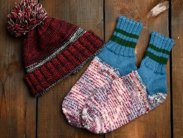 Paar Warme Bequeme Stricksocken Und Strickmütze Auf Braunem Holzhintergrund Ansicht — Stockfoto