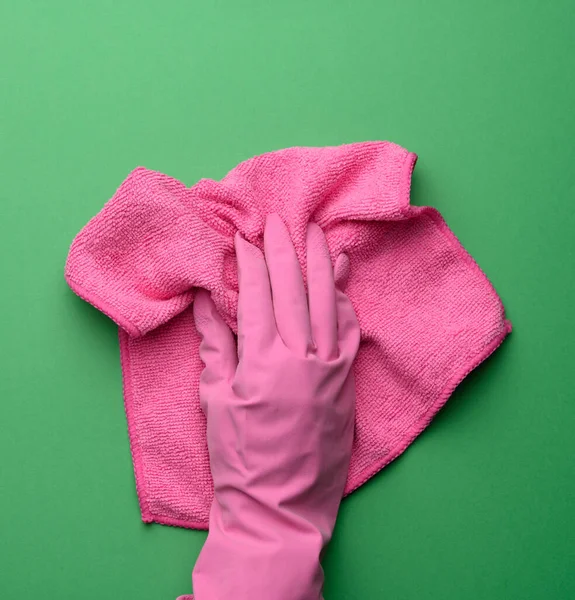 ピンクのゴム手袋の女性の手は紫色の背景にピンクのクリーニングラグを保持します — ストック写真