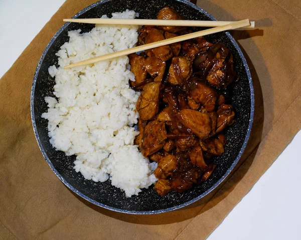 韩国烤鸡肉与白米和亚洲筷子在油锅中的褐色餐巾和白色背景 顶视图 — 图库照片