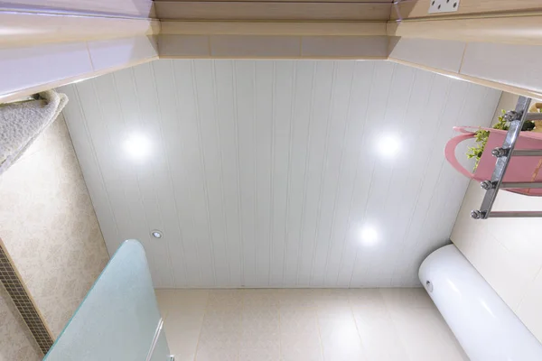 バスルームの天井には白い金属製のパネルが組み込まれ そのうちの1つが燃え尽きています — ストック写真