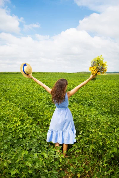 소녀는 노란색 꽃다발 밀짚모자를 들판에 — 스톡 사진