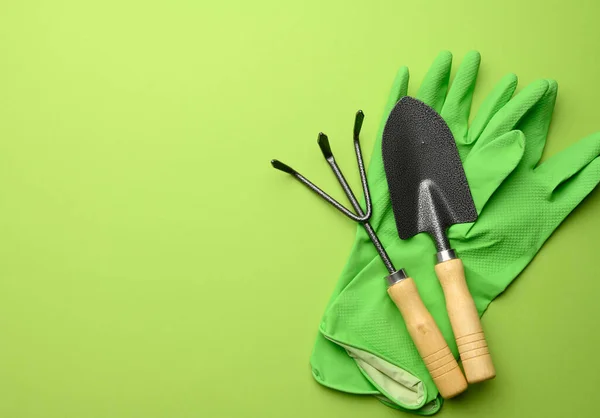 stock image green rubber gloves and garden set of shovels, rakes, pitchforks on a green background, top view, flat lay