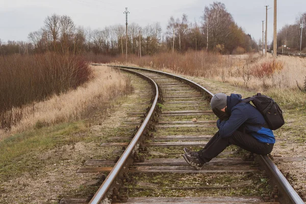 一个人独自坐在铁路上 用手捂住脸 感到悲伤 遗憾或恐惧 无法辨认的蒙面人 — 图库照片
