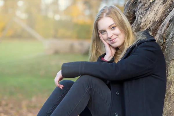 Portret Uśmiechniętej Dziewczyny Siedzącej Jesiennym Parku Dziewczyna Patrzy Kamerę — Zdjęcie stockowe