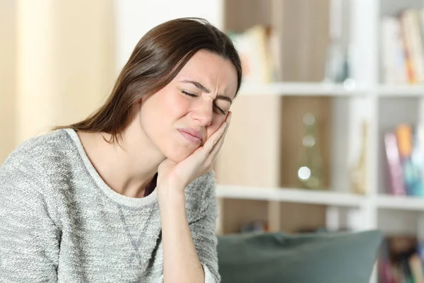 ストレスの多い女性苦しみ歯痛不平を言う頬に触れますカウチ上のホーム — ストック写真