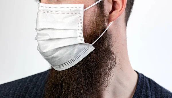 白の背景に隔離された汚染や伝染性のウイルスや病気を避けるために保護または外科マスクを身に着けている白人の若いひげを生やした成人男性 コロナウイルス 流行の概念を閉じる — ストック写真