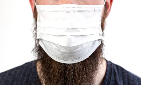 白の背景に隔離された汚染や伝染性のウイルスや病気を避けるために保護または外科マスクを身に着けている白人の若いひげを生やした成人男性 コロナウイルス 流行の概念を閉じる — ストック写真