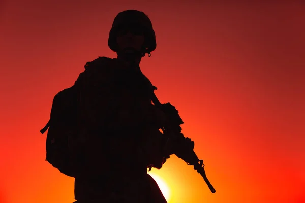 戴着头盔和弹药 背着战术背包 背着军用来复枪在夕阳的天空中行走的陆陆陆空军人的轮廓 反恐部队战士夜间行军 — 图库照片