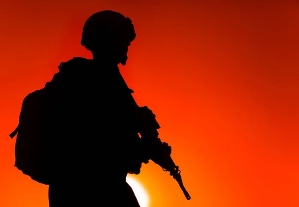 戴着头盔和弹药 背着战术背包 背着军用来复枪在夕阳的天空中行走的陆陆陆空军人的轮廓 反恐部队战士夜间行军 — 图库照片