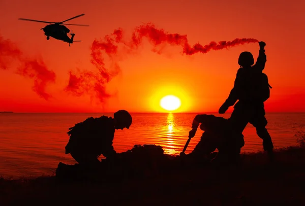 陸軍特殊部隊歩兵 海兵隊または海軍のシルエット水陸両用作戦中に海岸に上陸し 避難を待っている間煙のような雰囲気のヘリコプターに信号機チーム — ストック写真
