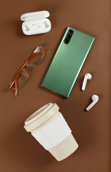 Smartphone Wiederverwendbare Kaffeetasse Drahtlose Kopfhörer Und Brille Auf Braunem Hintergrund — Stockfoto