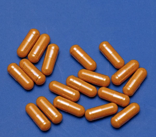 Grote Stapel Van Kurkuma Voedingssupplement Capsules Blauwe Achtergrond — Stockfoto