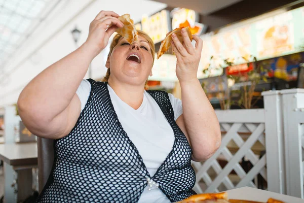 胖女人在商场餐厅吃披萨 吃不健康的食物 与垃圾晚餐 肥胖问题一起吃饭的超重女性 — 图库照片