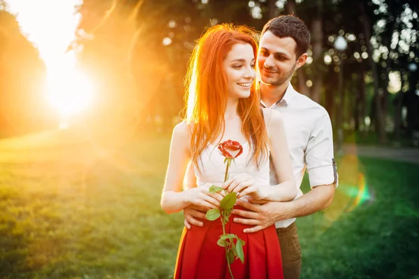 美丽的恋人在日落时拥抱 在户外浪漫地相遇 在公园里 迷人的玫瑰女子和年轻男子在一起悠闲自在 — 图库照片