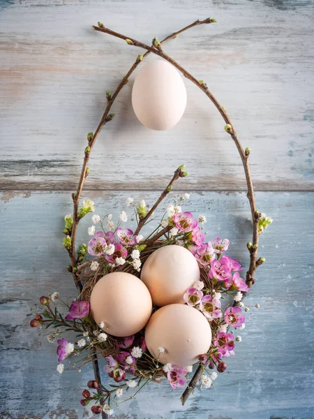 Easter still life with pastel colored eggs on a gray vintage planks. Floral easter decoration. Vertical flat lay photography with space for text. Top view.